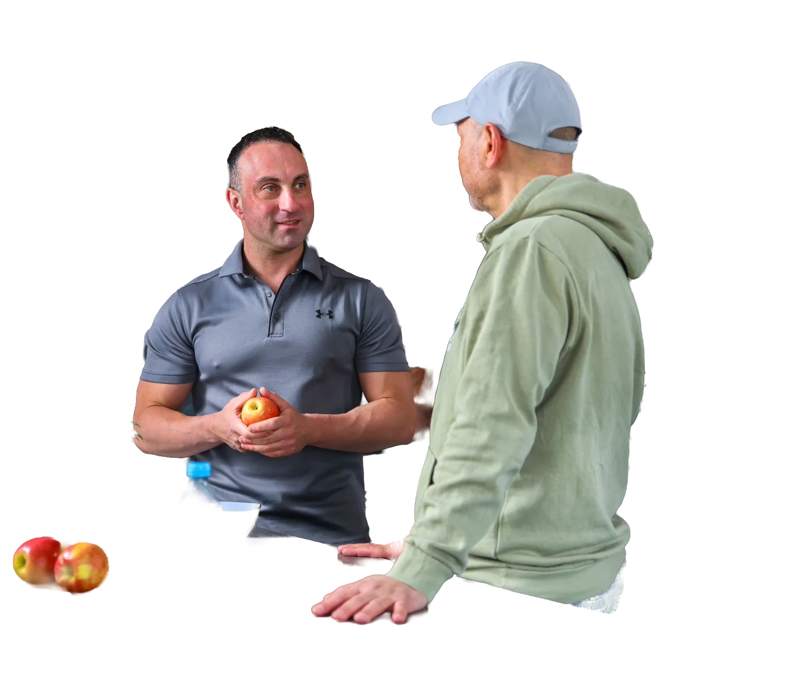 Nico Fichtler hält einen Apfel in den Händen und spricht in einer Küche mit einem Klienten, auf der Theke liegen Obst und eine Wasserflasche